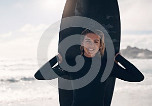 Surfing is pure joy. a young woman standing on the beach with her surfboard.