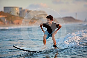 Surfing at Sunset. Young boy Riding Wave at Sunset. Outdoor Active Lifestyle