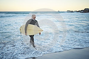 Surfing, surfboard and senior man on beach for water sports while walking on adventure after riding sea waves on a