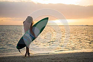 Surfing surfer girl looking at ocean beach sunset. Water sports with model.