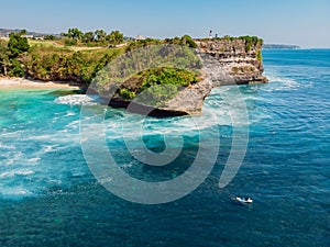 Surfing waves in blue ocean and cliff at background. Aerial view of tropical island with wave