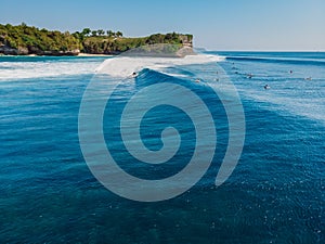 Surfing waves in blue ocean and cliff at background. Aerial view of tropical island with wave