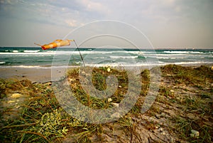 Surfing wind-sock on empty sea beach during storm