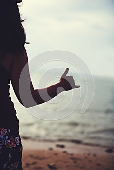 Surfs up. Rearview shot of a young woman at the beach gesturing hang ten.