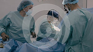 Surgeon with assisting man doctor operating patient perform surgical procedure. Nurse woman stand at table with medical