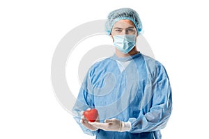 Surgeon in blue medical uniform and medical mask and holding toy heart