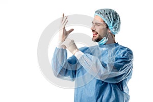 Surgeon in blue uniform and goggles wearing medical gloves