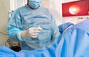 Surgeon in blue uniform working with equipment. Professional medical specialist working with instruments.
