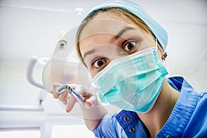 The surgeon dentist in mask holding forceps preparing for tooth extraction at clinic. Crazy dentist