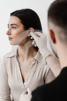 Surgeon doctor examines girl ear before otoplasty cosmetic surgery. Otoplasty is surgical reshaping of the pinna, or