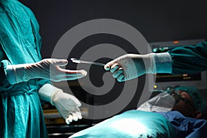 Surgeon doctor holding surgical scissors and passing surgical equipment to each other in the operating room at hospital.