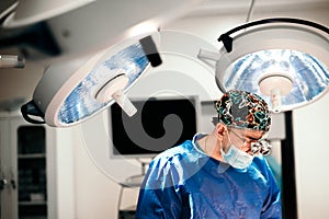 Surgeon doctor performing operation using special lamp lighting, wearing blue surgical mask photo
