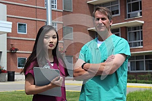 Surgeon, Doctor, Physician, Clinician and Asian Nurse Wearing Scrubs Stand in Front of Hospital photo