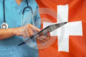 Surgeon or doctor using a digital tablet on the background of the Switzerland flag photo