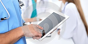 Surgeon doctor using tablet computer, close-up of hands at touch pad screen