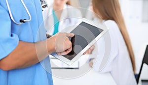 Surgeon doctor using tablet computer, close-up of hands at touch pad screen