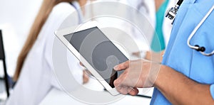 Surgeon doctor using tablet computer, close-up of hands at touch pad screen