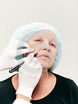 Surgeon doing skin check on mid age woman before plastic surgery