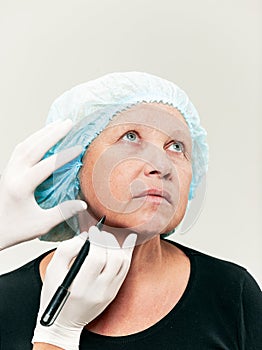Surgeon doing skin check on mid age woman before plastic surgery