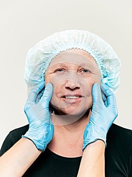Surgeon doing skin check on mid age woman before plastic surgery