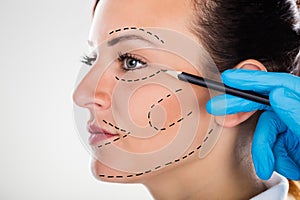 Surgeon Drawing Correction Lines On Young Woman Face photo