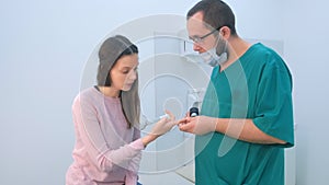 Surgeon examines wart on finger using dermatoscope magnifier before removing.