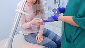 Surgeon explaining and showing woman how to remove wart using laser equipment.