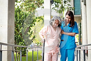 Surgeon holding the arm of an elderly patient while walking doing physical therapy.