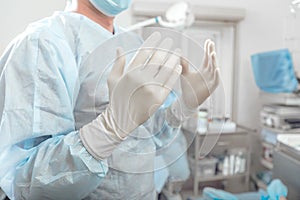 Surgeon holds hands up disinfected hands in white gloves before surgery