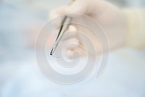 Surgeon holds in his hand a surgical needle