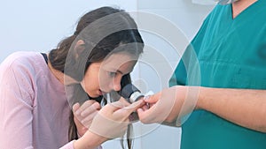 Surgeon and patient examine wart on finger using dermatoscope magnifier.