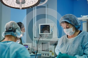 Surgeon performing cosmetic surgery in hospital operating room. Surgeon in mask wearing loupes during medical procadure