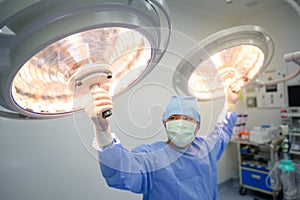 Surgeon or physician assistant Surgical lighting is being adjusted to light up when the medical team is working