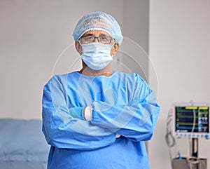 Surgeon, portrait and man with arms crossed in hospital with confidence in emergency healthcare, medicine or cardiology