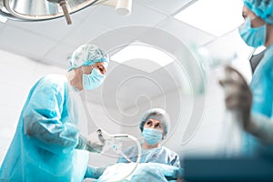 Surgeon in protective mask using laparoscope during surgery photo