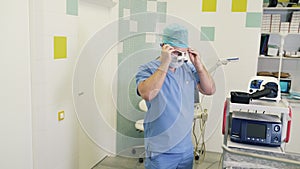 Surgeon puts on sterile mask and magnifying binocular glasses before surgery in operating room