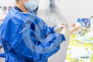 Surgeon putting on sterile gloves in an operating room.
