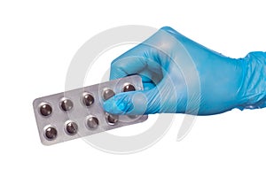 Surgeon`s hand in a blue medical glove holds a blister of tablets isolated on a white background