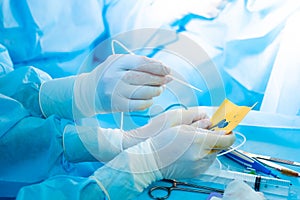The surgeon's hand in a sterile glove holds a fibrin glue dispenser.