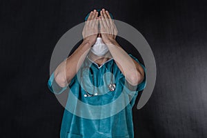 Surgeon in scrubs covering eyes.