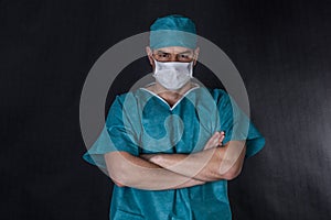 Surgeon in scrubs with hands folded.
