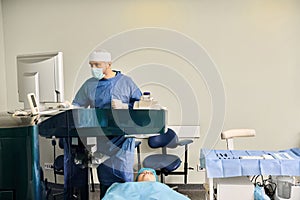 Surgeon in scrubs operating precision machine