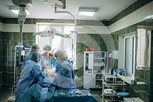 A surgeon sews up a patient in the operating room