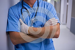 Surgeon standing with arms crossed in corridor at hospital