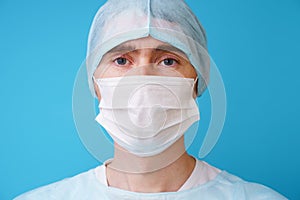 Surgeon in sterile blue uniform, medical gloves and mask