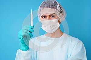 Surgeon in sterile blue uniform, medical gloves and mask