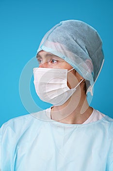 Surgeon in sterile blue uniform, medical gloves and mask