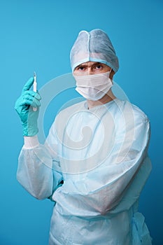 Surgeon in sterile blue uniform, medical gloves and mask