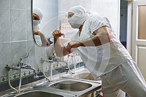 The surgeon turns off the water tap with his elbow after washing his hands. Hand treatment before surgery