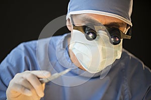 Surgeon Wearing Mask And Magnifying Glasses Holding Scalpel photo